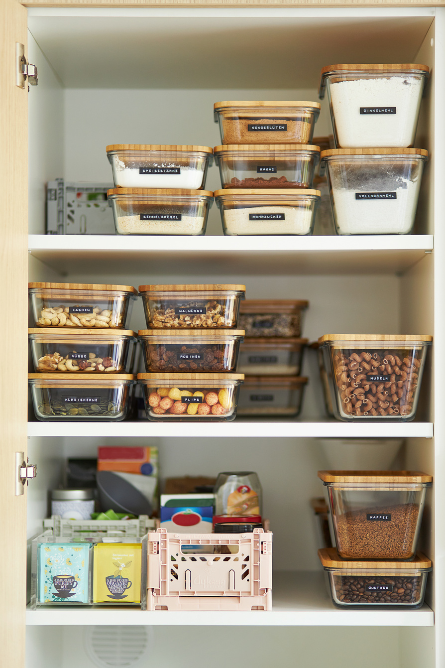 A middle-aged woman tidies up her cupboard in the kitchen and reorganizes everything